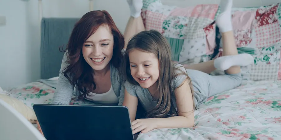 Mãe e filha sorrindo diante do notebook em videochamada, cuidado com cardiopatia infantil em Portugal