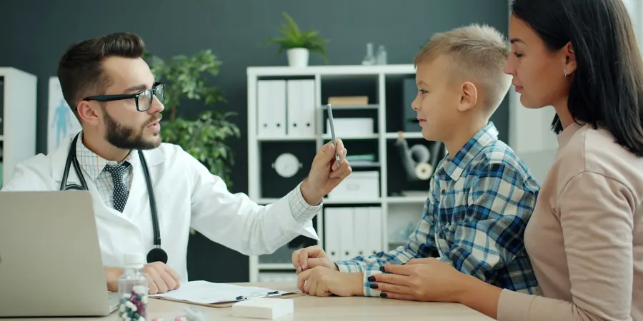 Pediatra conversa com um menino e a mãe na primeira consulta com cardiologista pediátrico