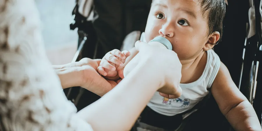 Bebê tomando mamadeira segurada pela mãe, atenção aos sinais de cardiopatia em bebê