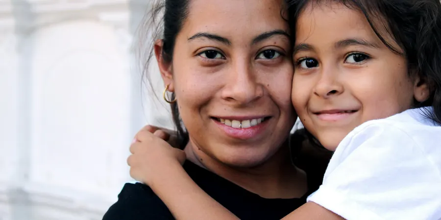 Mãe e filha abraçadas e sorrindo, família que convive com a síndrome do QT longo em crianças