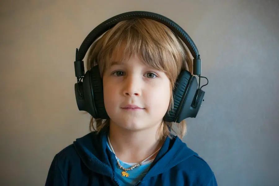 Menino com fones de ouvido olhando para a câmera: o cardiologista para crianças com TDAH e TEA adapta a consulta à sensibilidade sensorial